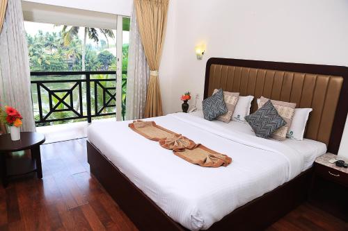a bedroom with a large white bed with a balcony at AQUARIA THE BOUTIQUE RESORT in Cochin