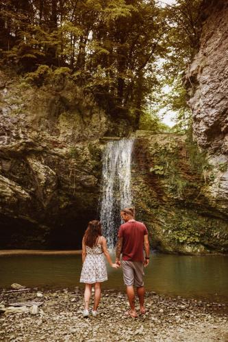 a man and woman standing in front of a waterfall at Hotel Thermana Park Laško**** Superior in Laško