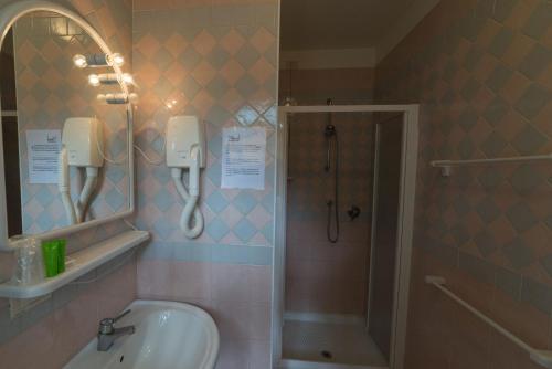 a bathroom with a shower and a sink and a mirror at Hotel Airone in Bibione