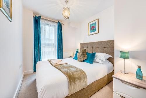 a bedroom with a large bed with blue curtains at Self-contained town centre apartment Queensgate nr Marketfield by Helmswood Serviced Apartments in Redhill