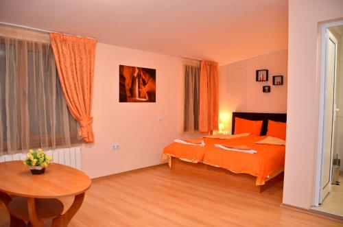 a bedroom with an orange bed and a table at Стаи за Гости Тони и Крис in Devin