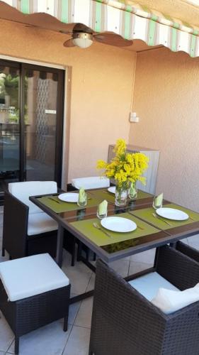 uma mesa com cadeiras e um vaso de flores amarelas em Comfortable Air Conditioned Studio With Terrace em Bandol