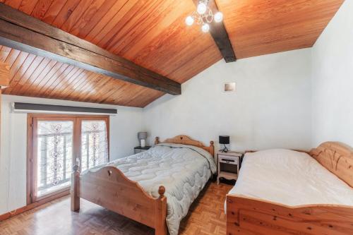 two beds in a bedroom with a wooden ceiling at Appartement accueillant à Saint-Martin-de-Belleville in Saint-Martin-de-Belleville
