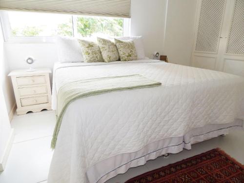 ein weißes Bett in einem weißen Schlafzimmer mit einem Fenster in der Unterkunft Leblon House I in Rio de Janeiro