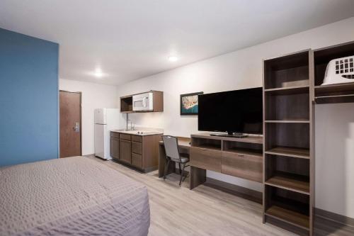 a hotel room with a bed and a desk with a television at WoodSpring Suites Detroit Madison Heights in Madison Heights