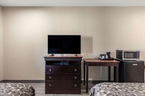 a hotel room with a tv on a dresser with a desk and a television at Rodeway Inn in Caldwell