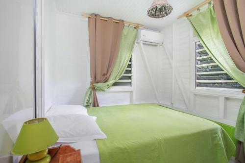 a bedroom with a green bed and a window at Bungalow charmant à Rivière-Salée avec terrasse privée in Rivière-Salée