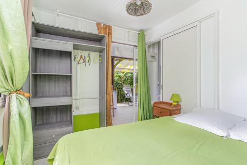 a bedroom with a green bed and a sliding glass door at Bungalow de 2 chambres avec terrasse amenagee et wifi a Riviere Salee a 9 km de la plage in Rivière-Salée