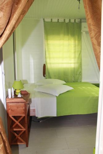 a bedroom with a green bed and a wooden table at Bungalow charmant à Rivière-Salée avec terrasse privée in Rivière-Salée