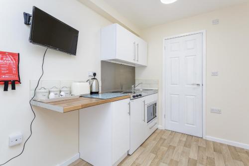 a kitchen with white cabinets and a tv on the wall at Blackberry - Stylish Self-Contained Flats in Soton City Centre in Southampton