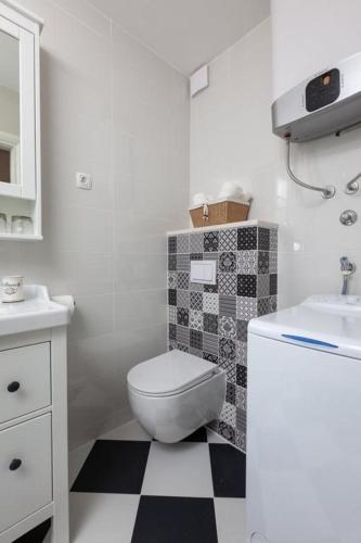 a white bathroom with a toilet and a sink at APARTMANI Mirona - Tučepi in Tučepi
