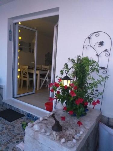 a porch with a lamp and some flowers and a table at APARTMANI Mirona - Tučepi in Tučepi