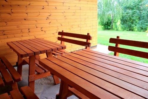 two wooden benches sitting next to a brick wall at Domek letniskowy Smreczyny Bobra in Jeziorko