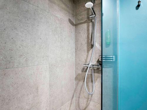 a shower with a glass door in a bathroom at Mövenpick Hotel München-Airport in Hallbergmoos