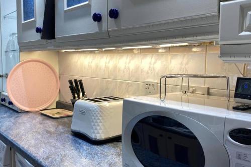 a kitchen with a microwave and a toaster oven on a counter at Comfy Home- Coley Park in Reading