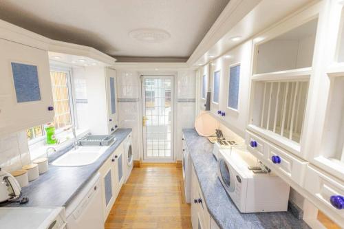 uma grande cozinha branca com 2 lavatórios e um micro-ondas em Comfy Home- Coley Park em Reading
