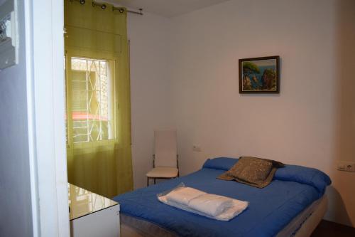 Un pequeño dormitorio con una cama azul y una ventana en Casa Martinet, en Sant Feliu de Guíxols