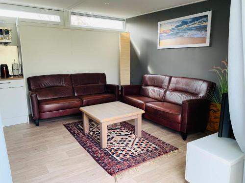 a living room with two leather couches and a coffee table at Huisje nummer 3 in Goedereede