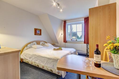 a bedroom with a bed and a table with a bottle of wine at Haus Ostseeglück - Ferienwohnung Mittagssonne mit Gemeinschaftssauna in Loddin