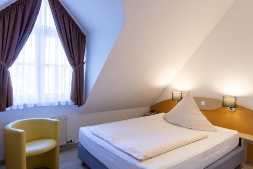 a bedroom with a bed and a chair and a window at Hotel Alte Mühle in Chemnitz