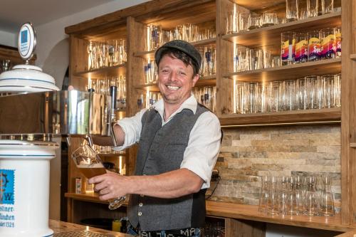 a man is holding a glass in a bar at LandererMühle in Lenggries