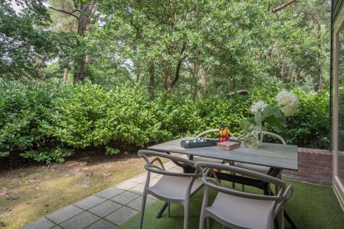 a table and chairs on a patio with trees at Vakantiepark Zevenbergen in Heesch