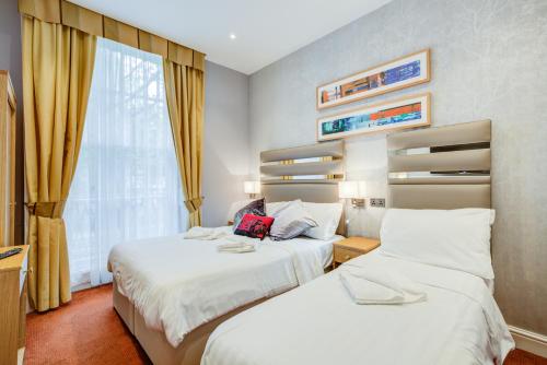 ein Hotelzimmer mit 2 Betten und einem Fenster in der Unterkunft KingswayPark Hotel at Park Avenue in London