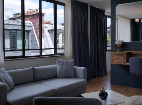 a living room with a couch and large windows at Hotel Bachaumont in Paris