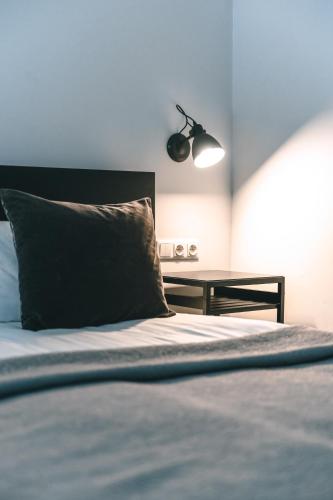 a bed with a black pillow and a table at Brother House Kaunas in Kaunas