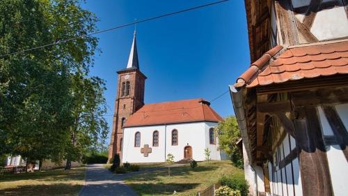 a small white church with a steeple on a street at Quartier vert in Hunspach