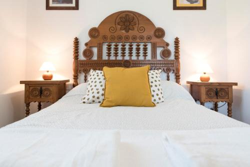 a bed with a wooden headboard and pillows on it at Apartamentos Alegría in Santillana del Mar