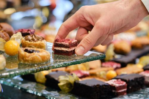 a person reaching for a piece of cake on a display of desserts at SPA Resort St Ivan Rilski - Halfboard & All Inclusive in Bansko