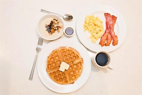 a table with two plates of waffles and bacon at Staybridge Suites - Denver North - Thornton by IHG in Thornton