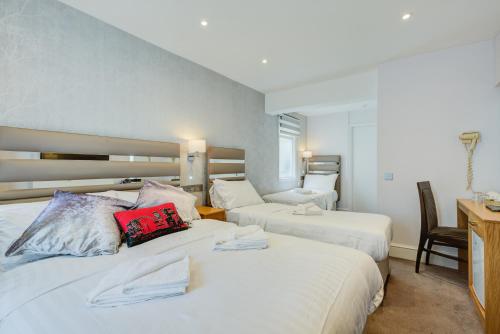 ロンドンにあるキングスウェイパーク ホテル アット パーク アヴェニューのベッド2台とデスクが備わるホテルルームです。