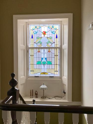 Creity Hall Guest House في Doune: نافذة زجاجية ملطخة في الحمام مع حوض استحمام