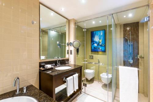 a bathroom with a tub, sink, mirror and toilet at Asiana Hotel Dubai in Dubai