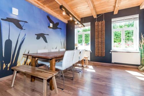 une salle à manger avec une table en bois et des dauphins peints sur le mur dans l'établissement B&B Lisdodde, à Lissewege