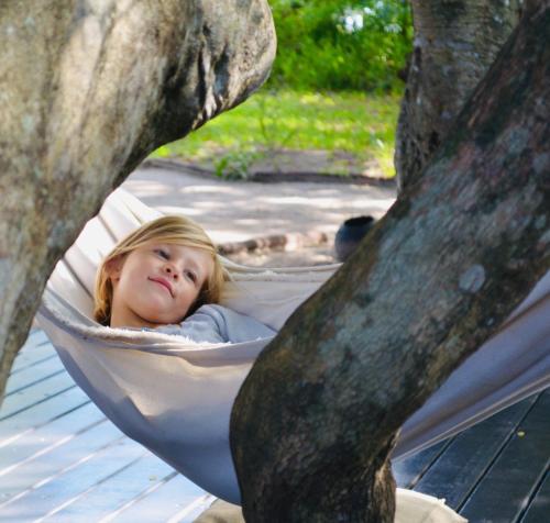 a little girl laying in a hammock in a tree at B&B Lisdodde in Lissewege