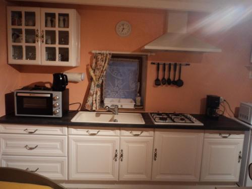 a kitchen with white cabinets and a microwave and a sink at Gîte La Lieutenance in Saint-Pourçain-sur-Sioule