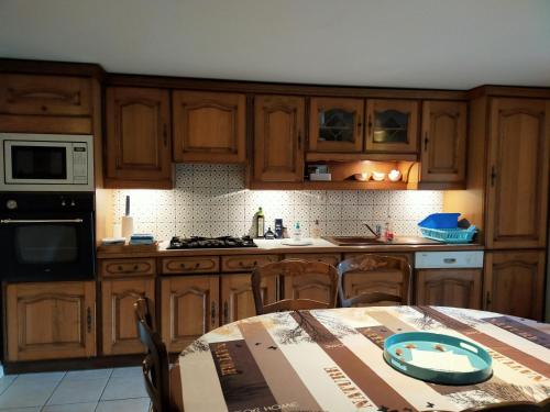 una cocina con armarios de madera y una mesa con una caja. en La petite maison bleue en Lopérec