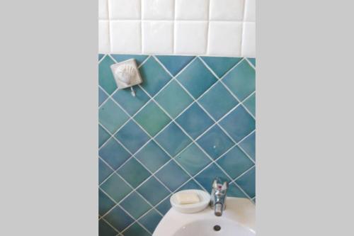 a bathroom with a toilet and a blue tiled wall at Chia Delizioso nido verde nel blu in Chia