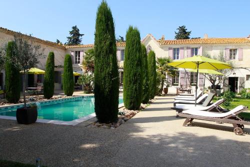 un complejo con una piscina con sillas y sombrillas en Mas de la Fosse, en Saint-Gilles