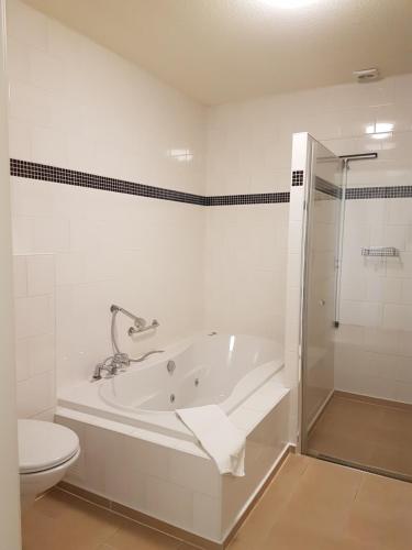 ein weißes Bad mit einer Badewanne und einem WC in der Unterkunft Hotel Garni Am Lindenhof Bunde in Bunde