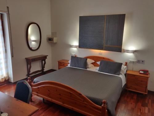 1 dormitorio con cama grande de madera y espejo en Hotel Il Rustichello, en Lonato