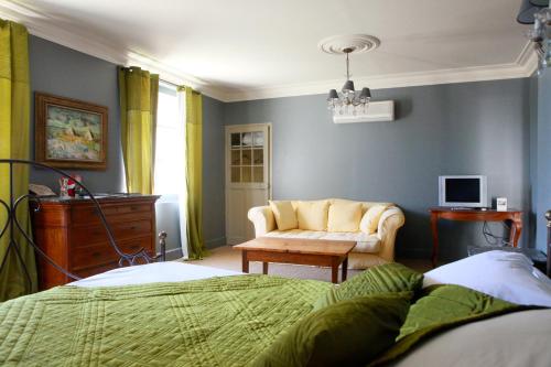 a bedroom with a bed and a couch and a chair at Mas de la Fosse in Saint-Gilles
