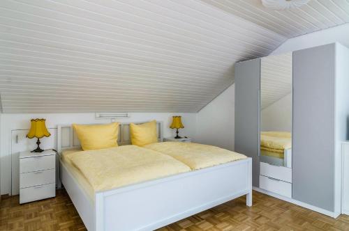 a white bedroom with a large bed with yellow pillows at Ferienwohnung Maria Feucht in Überlingen