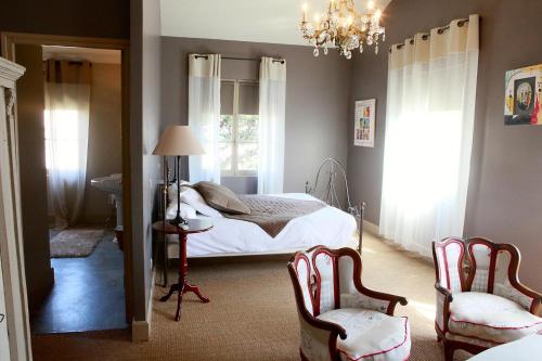 1 dormitorio con 1 cama, 2 sillas y lámpara de araña en Mas de la Fosse, en Saint-Gilles