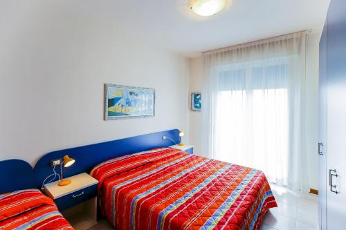 a bedroom with a blue and red bed and a window at Tamerici Lido Altanea in Caorle