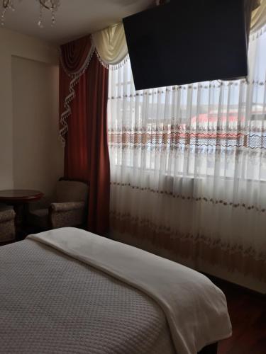 a bedroom with a bed and a window with curtains at Hostal Terrabella SRL in La Paz