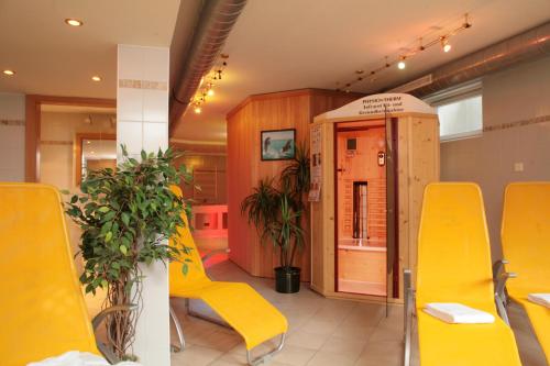 a restaurant with yellow chairs and plants in a room at der Wildbachhof - Contactless check in in Zell am See